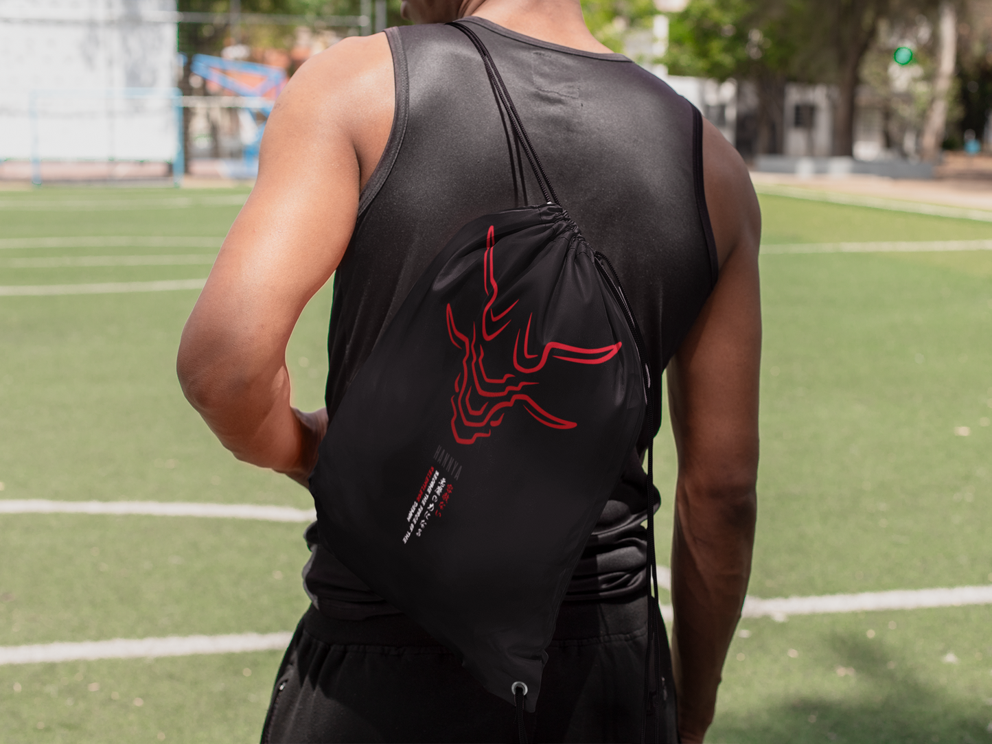Hannya red drawstring bag on male model facing backward at football pitch