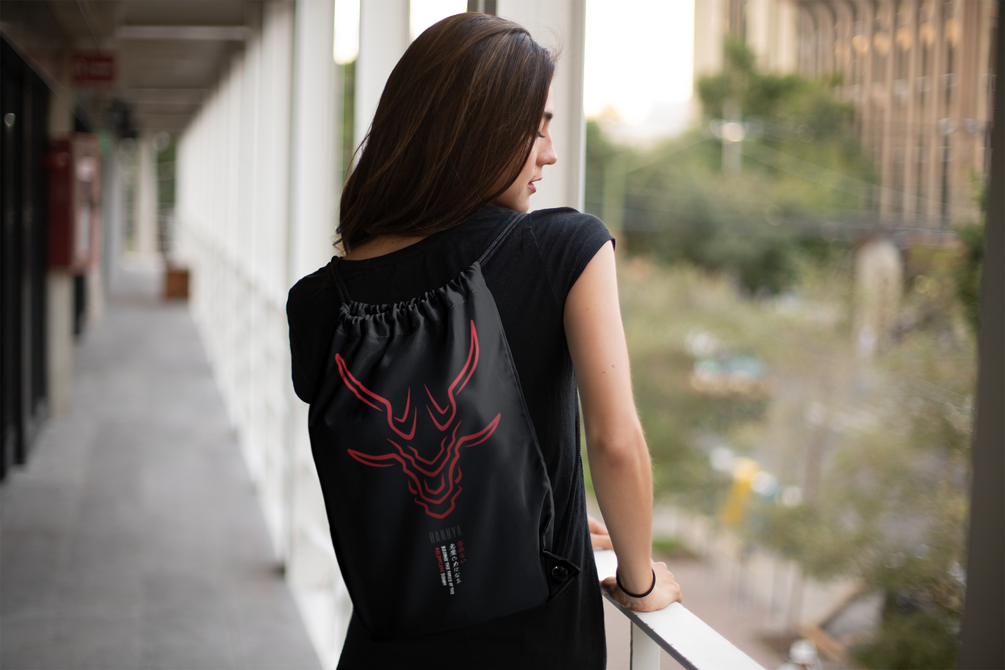Hannya red drawstring bag on female model facing backward at open hallway