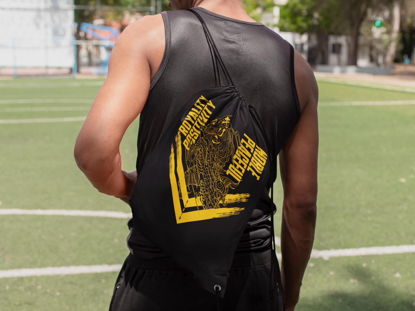 Kirin yellow drawstring bag on male model facing backward at football pitch