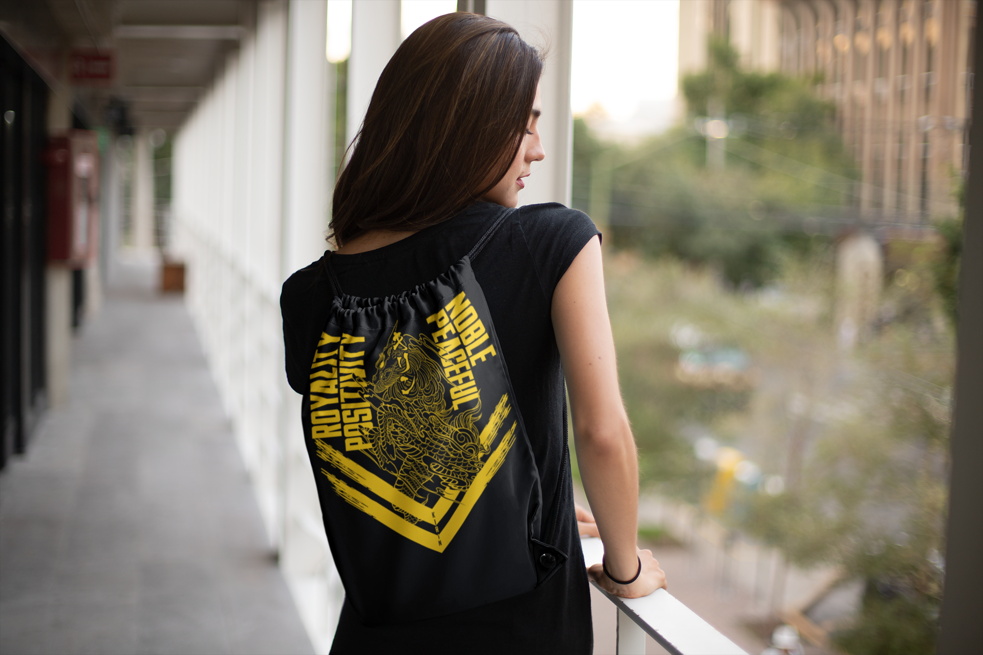 Kirin yellow drawstring bag on female model facing backward at open hallway