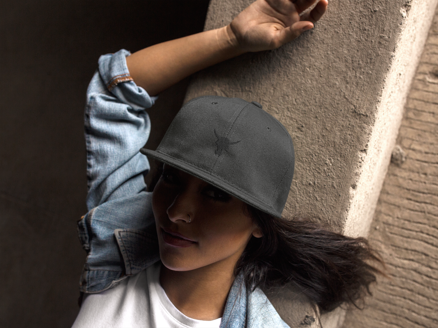 Female model with retro trucker hat leaning towards dry wall
